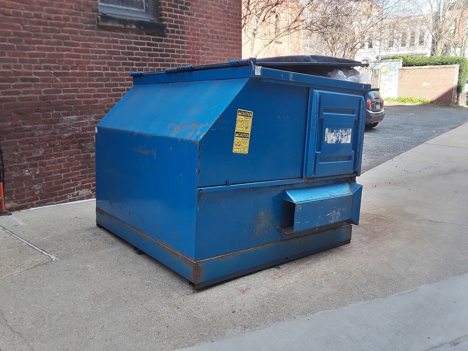 A blue dumpster in an alley, second angle