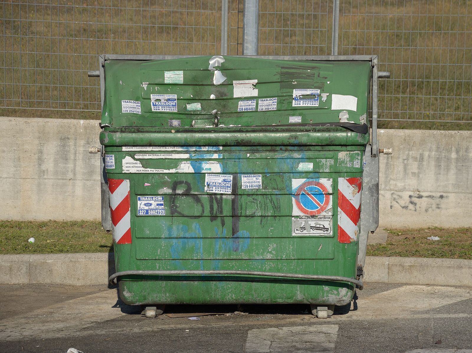 A green dumpster with stickers