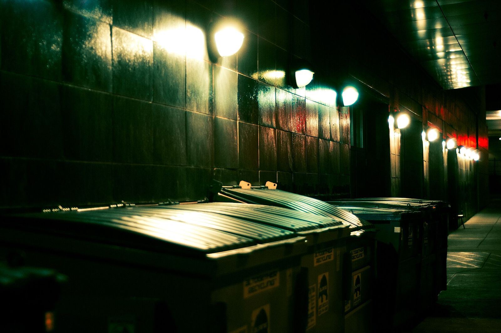 Two dumpsters alone in a parking lot at night