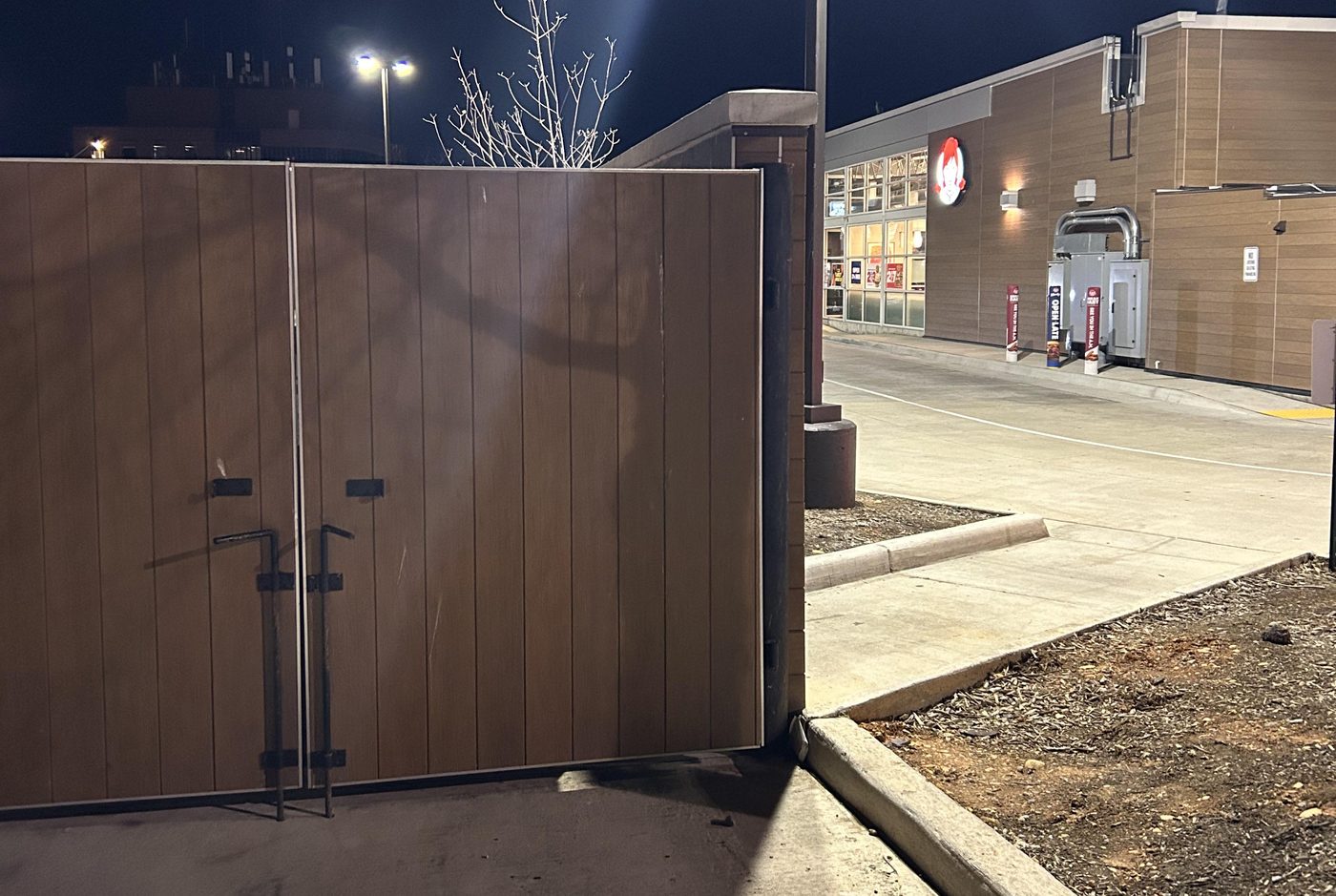A dumpster enclosure behind a Wendy's at night